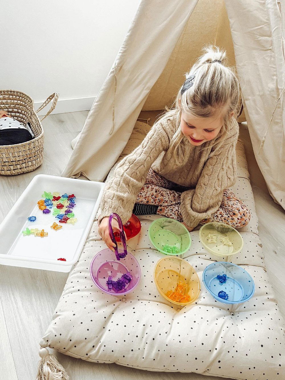 Gekleurde insecten 48 stuks - yourlittlefamily-nl - Meisje is met een pincet de gekleurde insecten in het gekleurde bakje te doen. Kleuren leer en sensomotorisch spel
