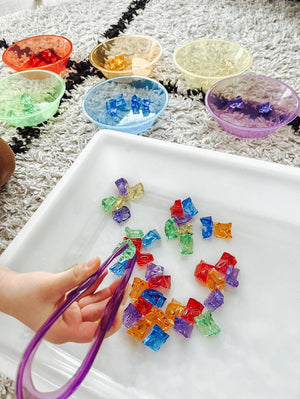 Gekleurde sorteerstenen 60 stuks - yourlittlefamily-nl - Verschillende gekleurde stenen in witte bak met pincet. Druk aan het spelen.